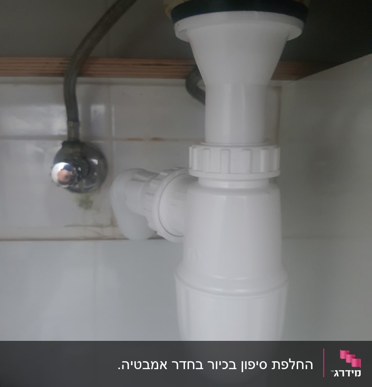 צינור פלסטיק לבן מתחת לכיור עם חיבורי מתכת
